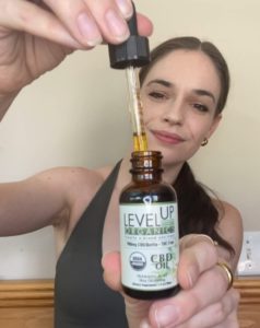 Woman holding up a dropper of CBD Oil